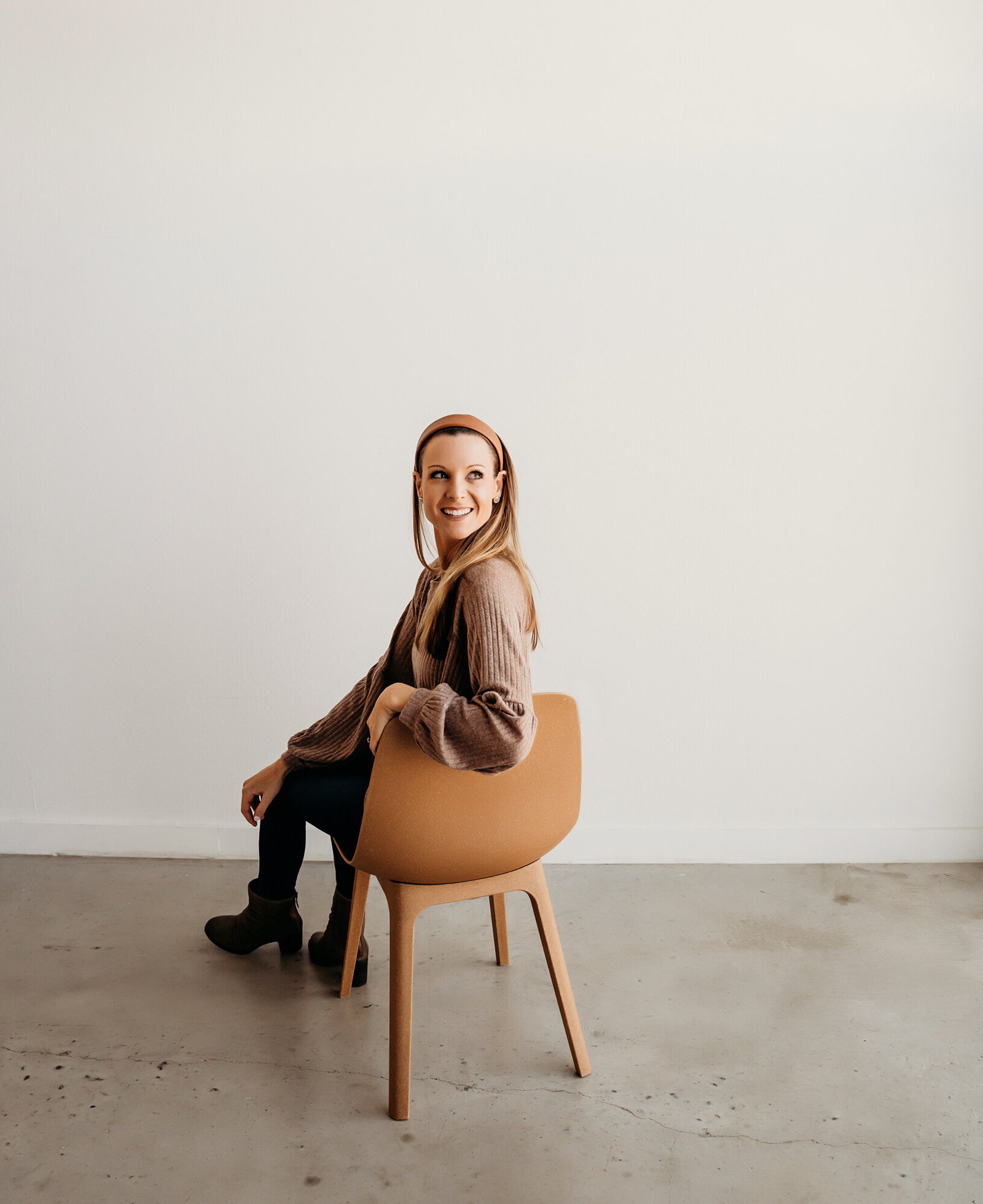 Branding Photographer,  in an empty room a woman turns back from her chair and smiles
