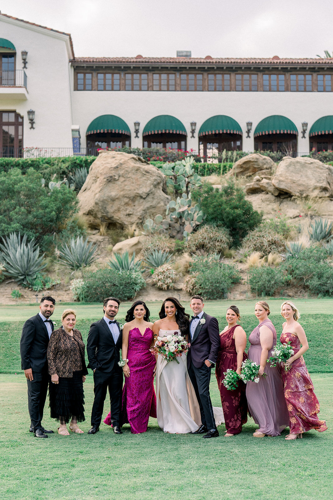 Colorful full wedding party portrait in front of Hummingbird Nest Ranch’s Spanish architecture, styled in fine art film.