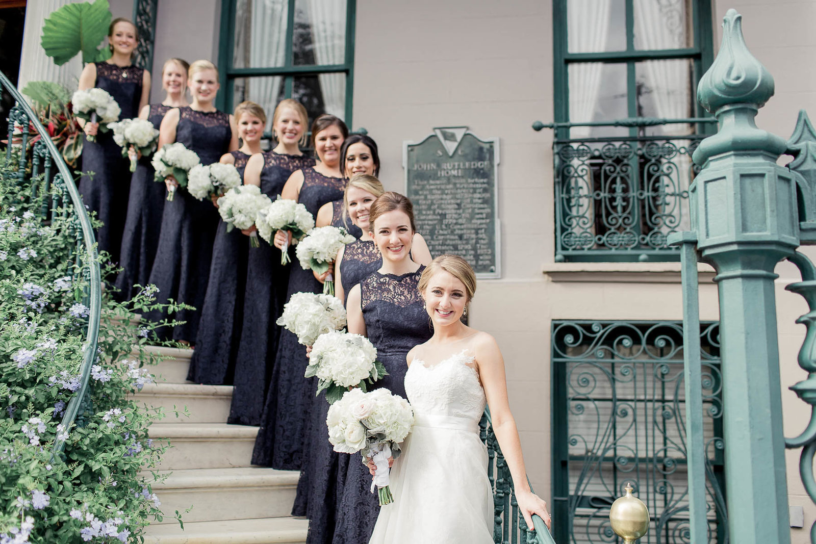 Bride poses with bridesmaids on ornate staircase, John Rutledge House Inn, Charleston, South Carolina