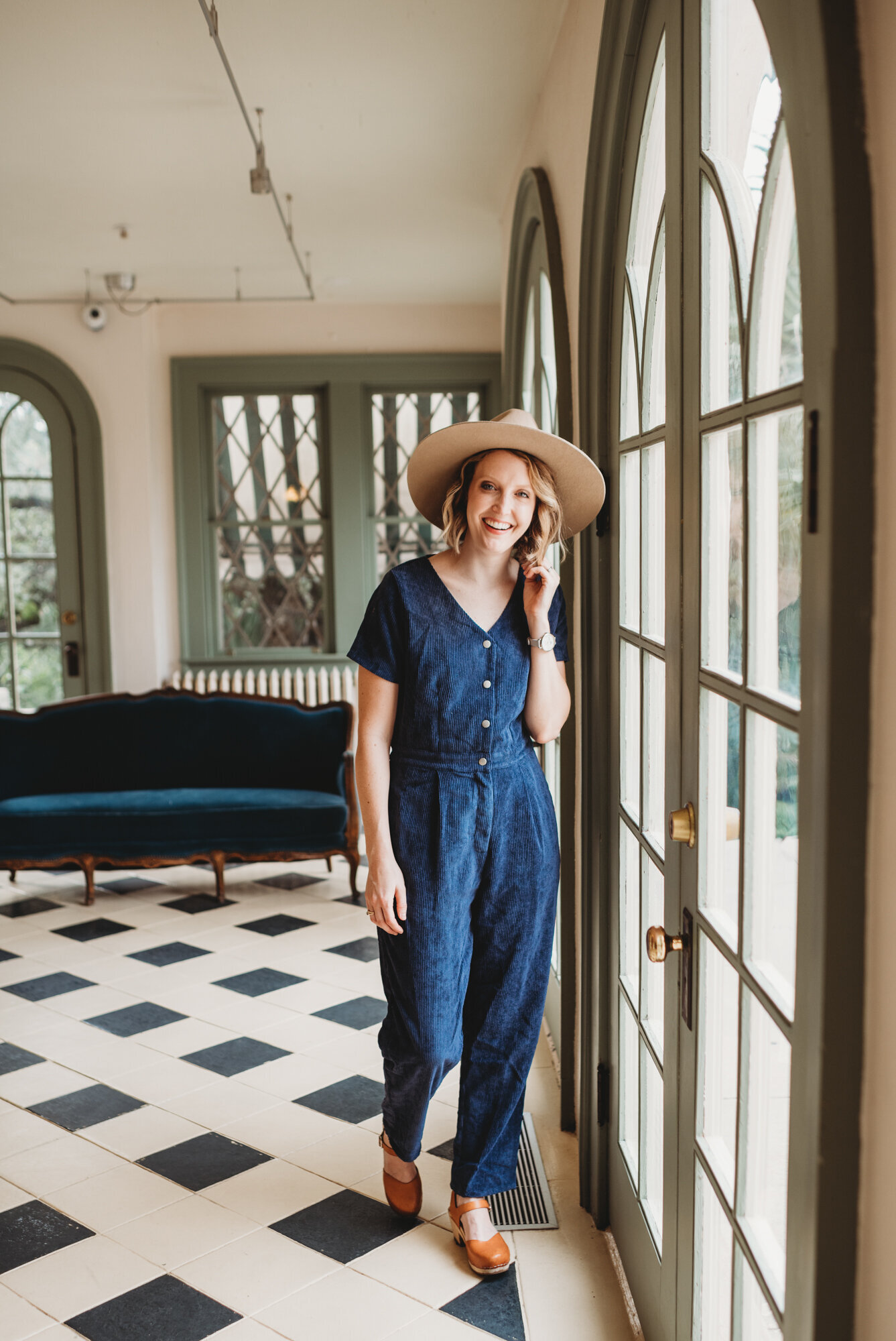Branding Photographer,  a woman wears a romper and hat as talks on the phone and walks in her home