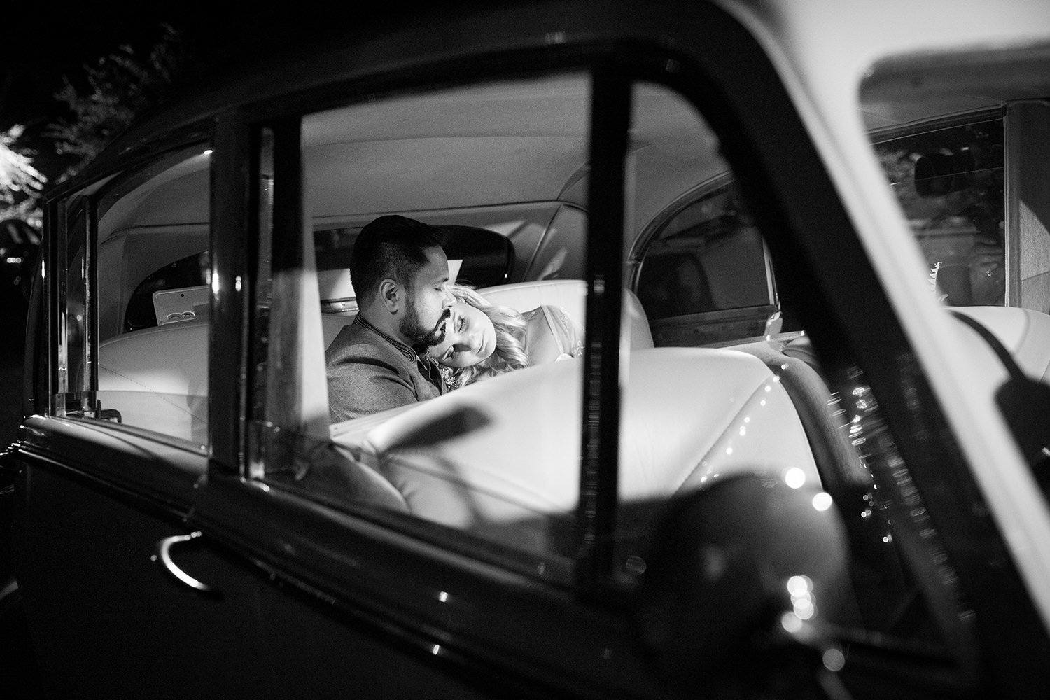 Creative portrait of bride and groom snuggling in the back of a vintage car