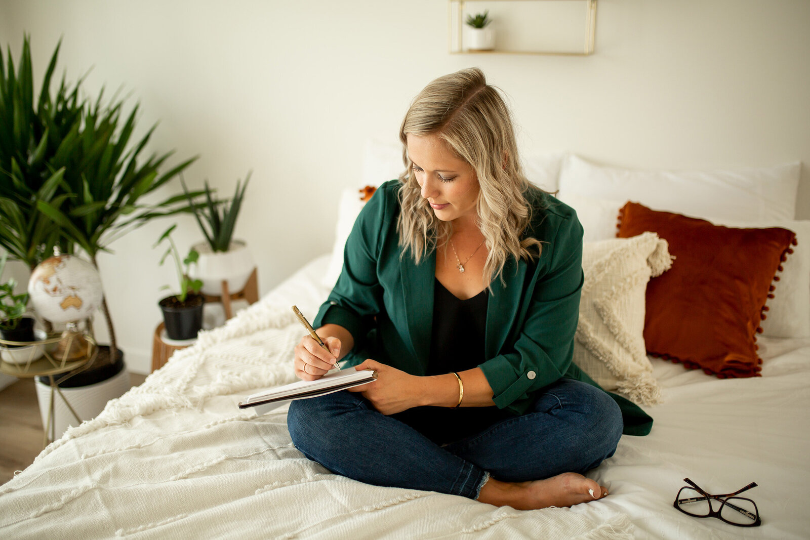 woman sitting on bed writing in planner