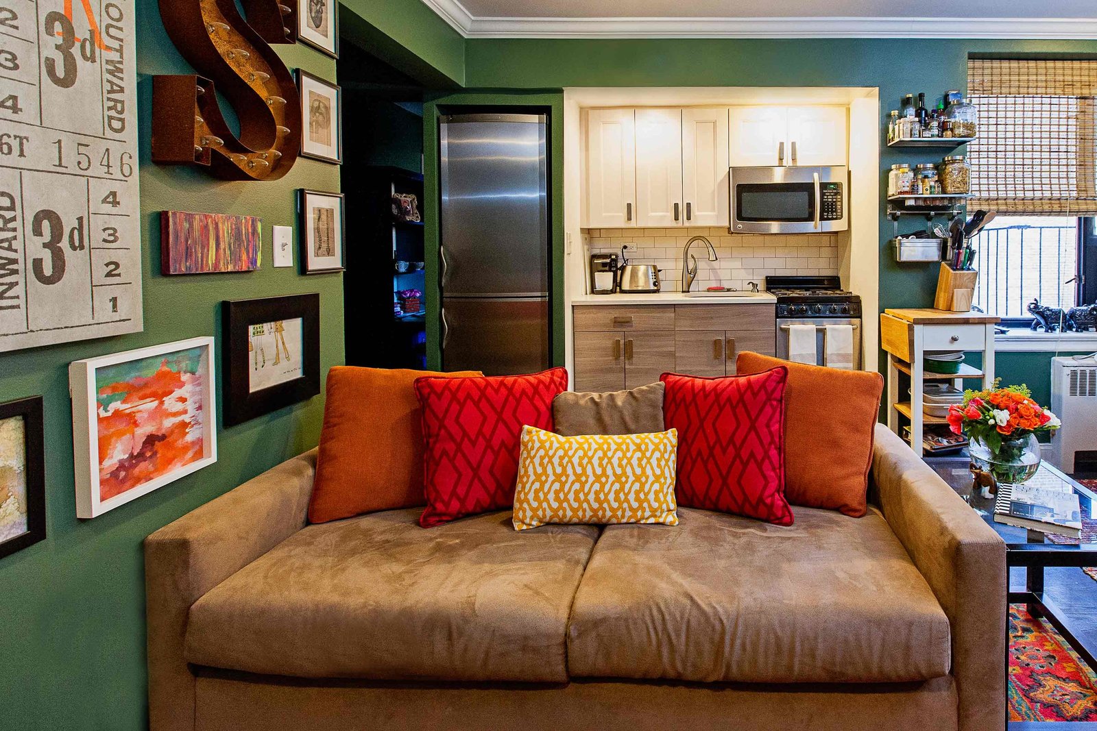 A brown couch in front of a studio apartment kitchen.