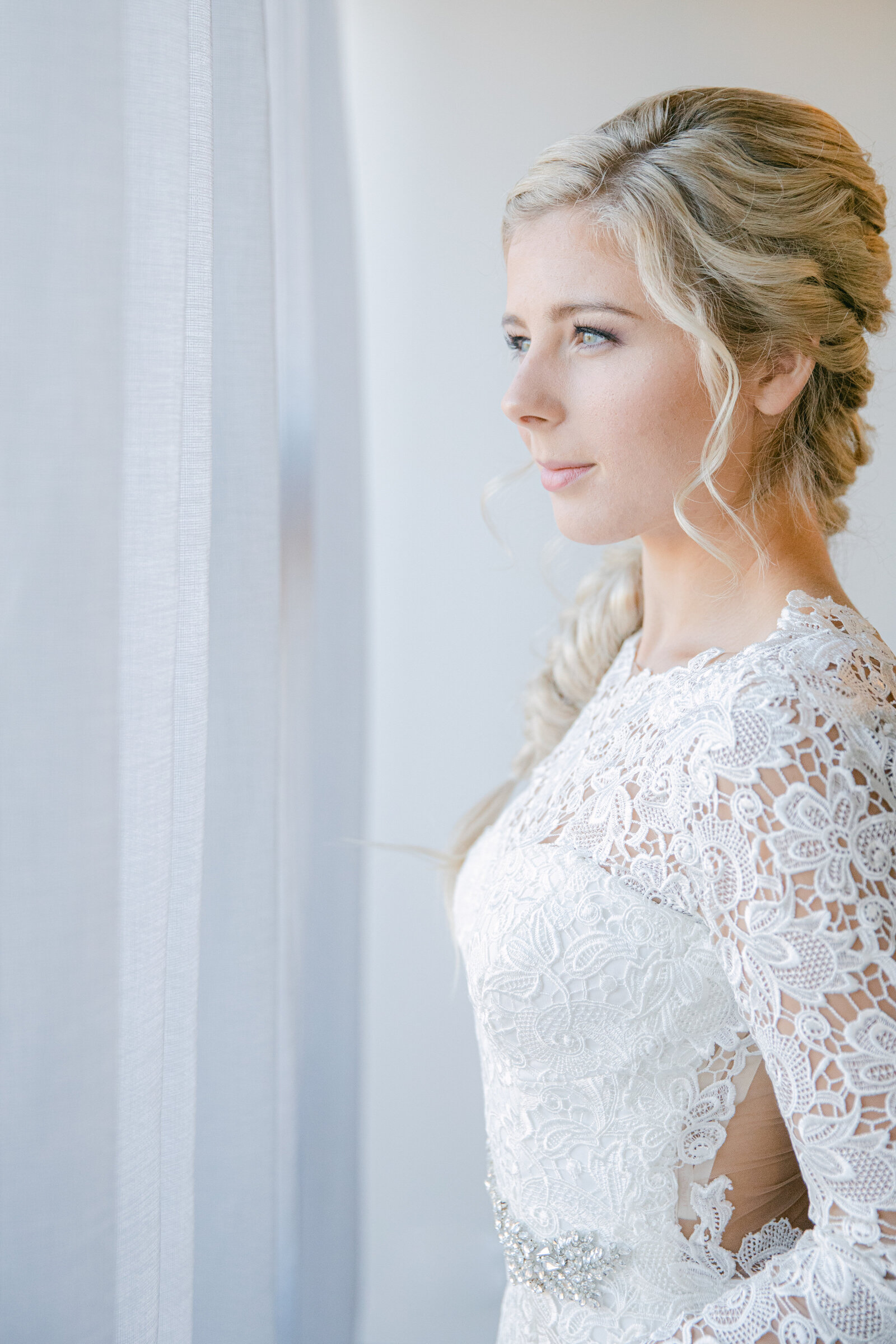 bride in lace dress looking out the window