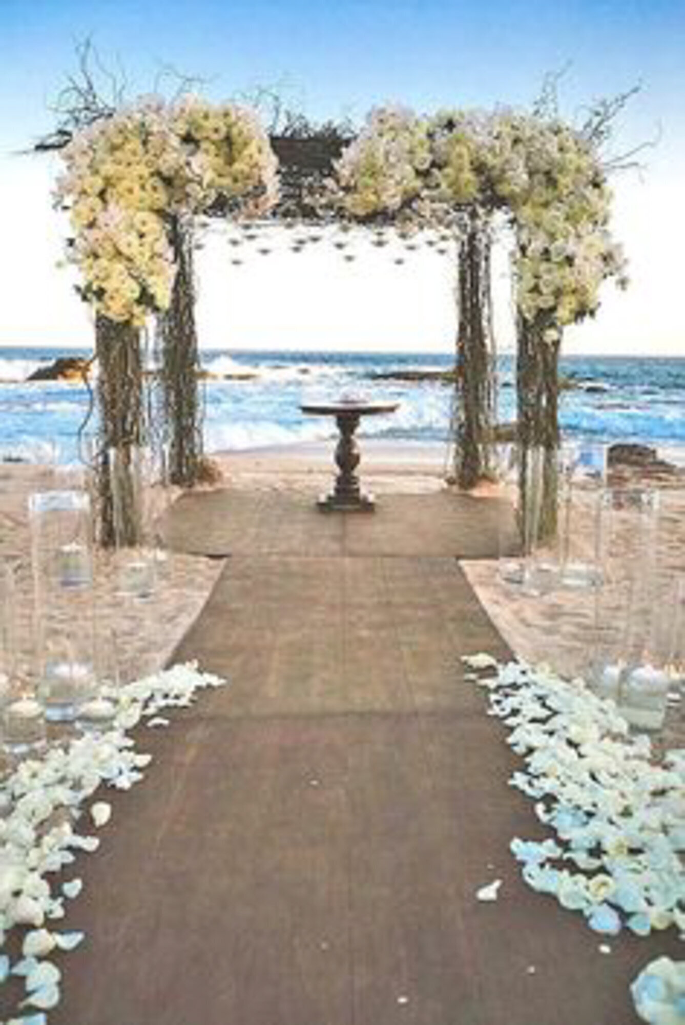 Beach wedding ceremony site with floral arch backdrop and aisle