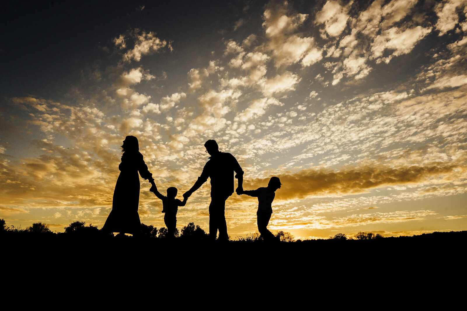 silhouette of family of four at sunset