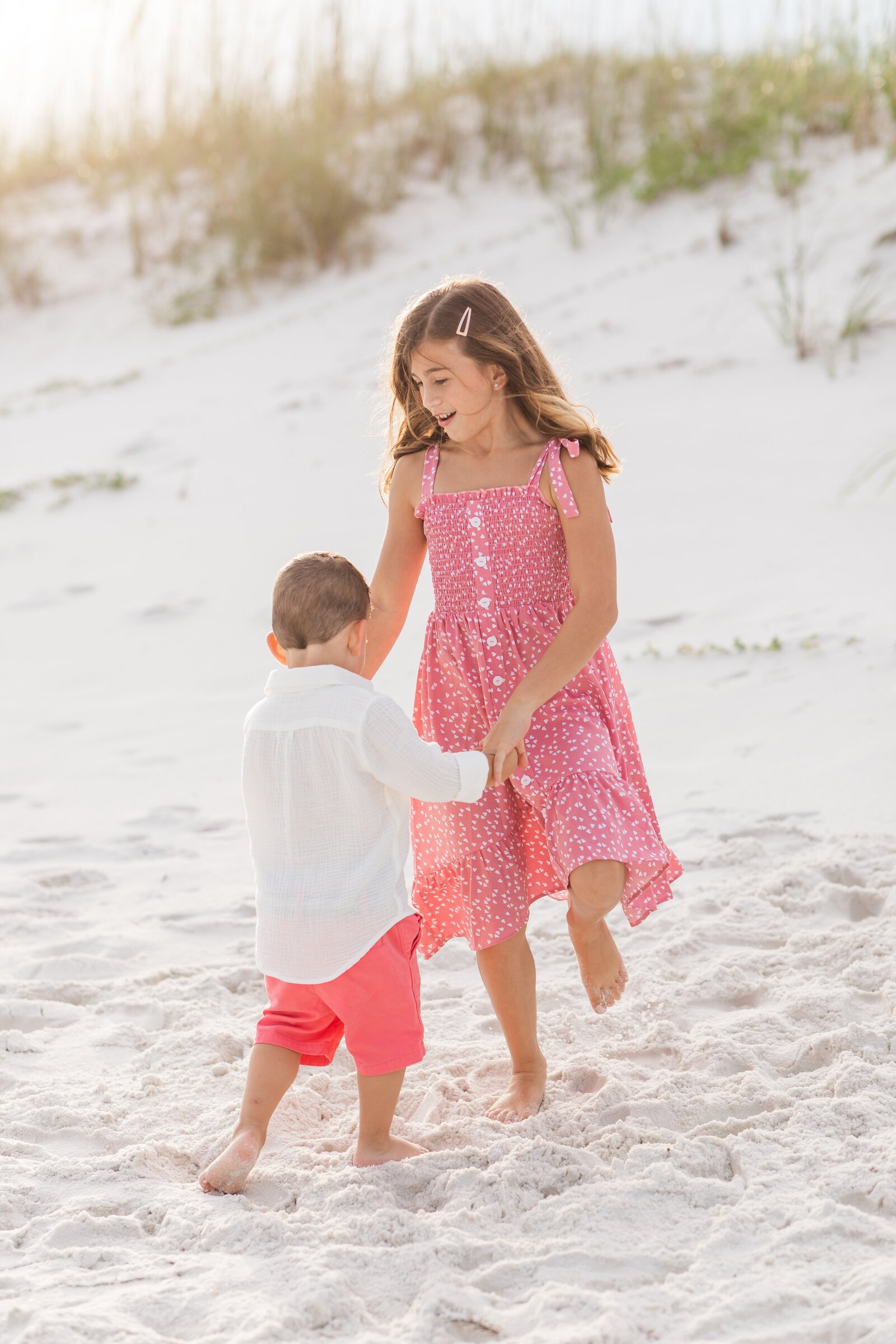 Pensacola Beach vacation family photo session .  Brother and sister playing ring around the rosy in the sand.