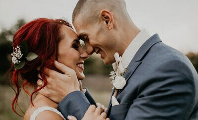 Close up of bride and groom smiling and hold heads close together.