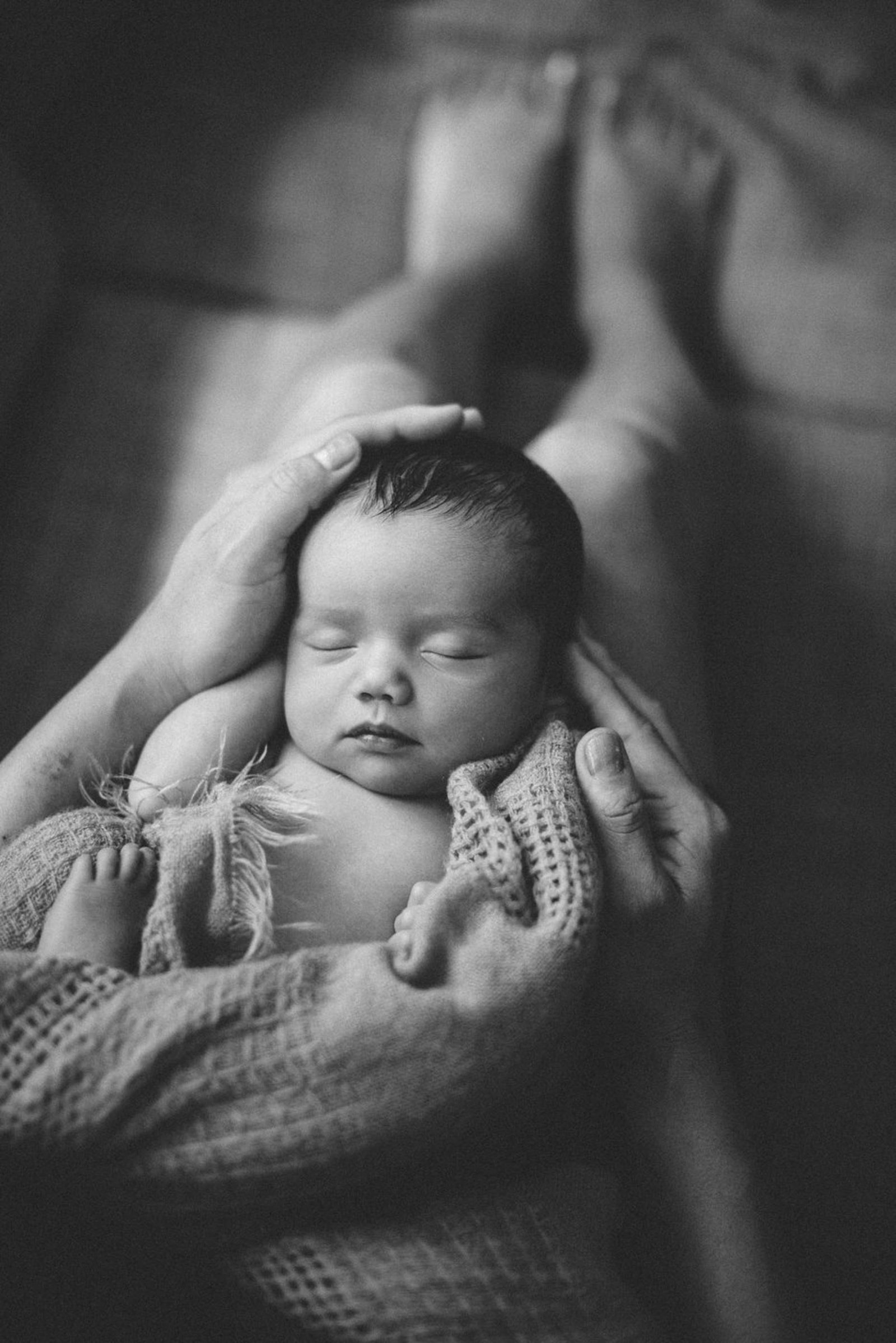 black and white photo of newborn in mother's lap at home