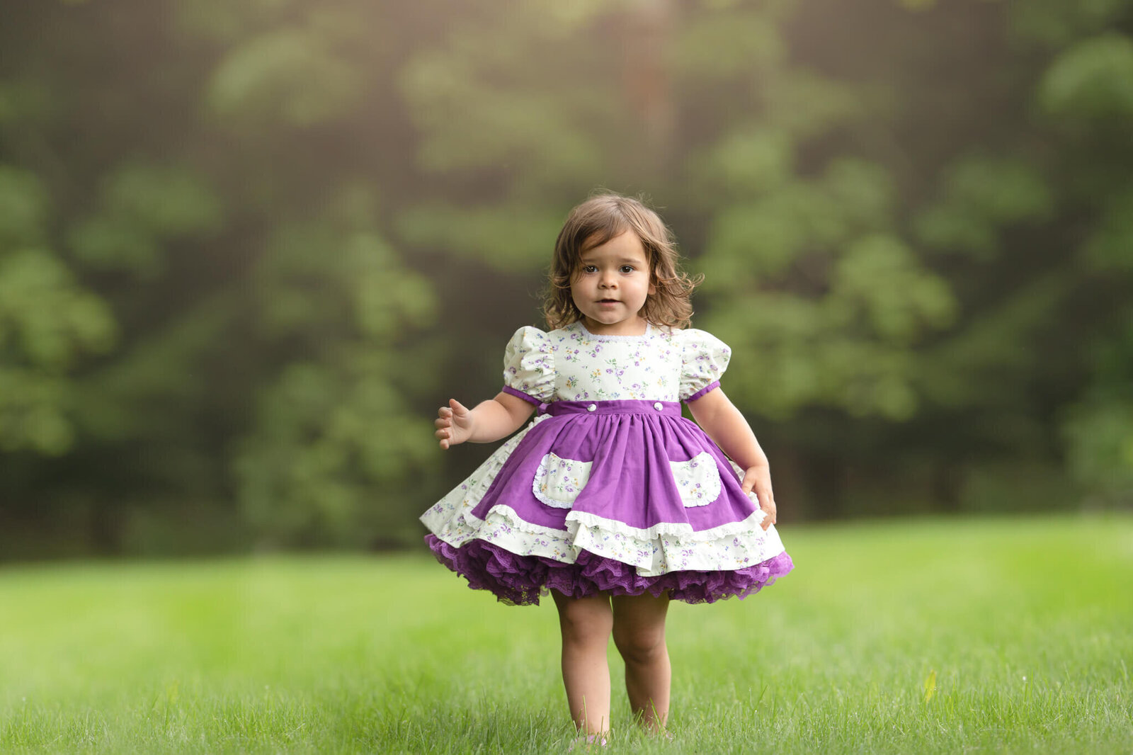 Little girl in purple floral dress walking towards camera