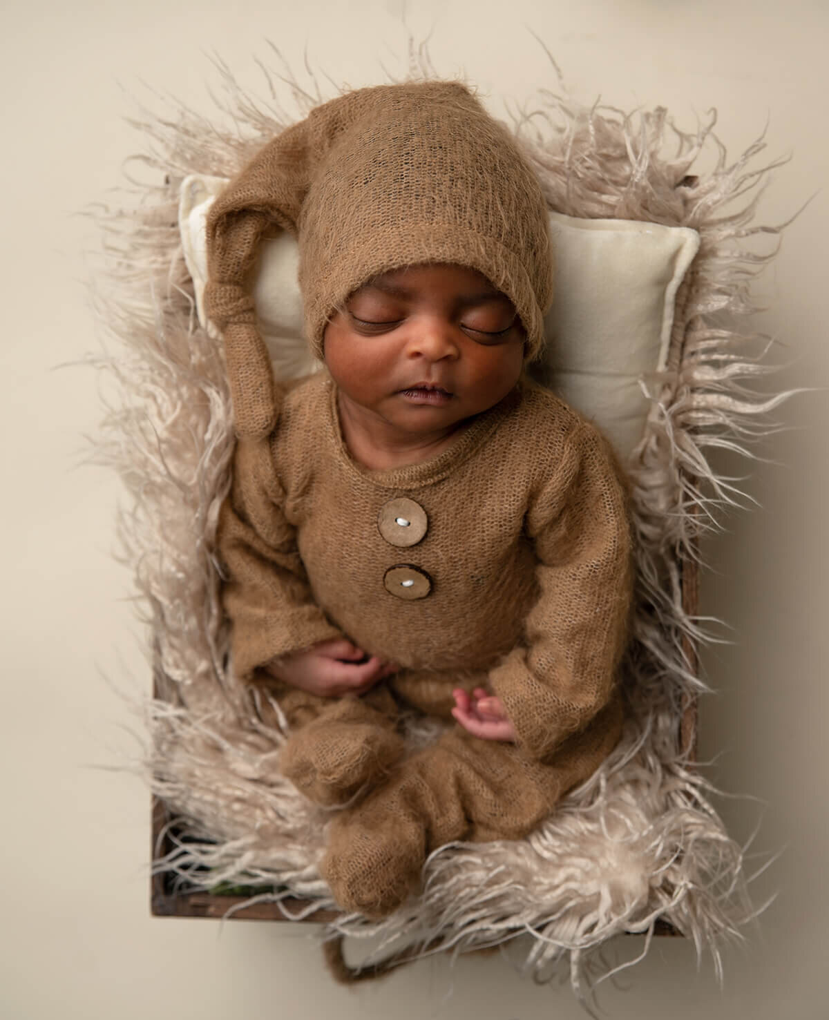 newborn baby wearing a brown romper