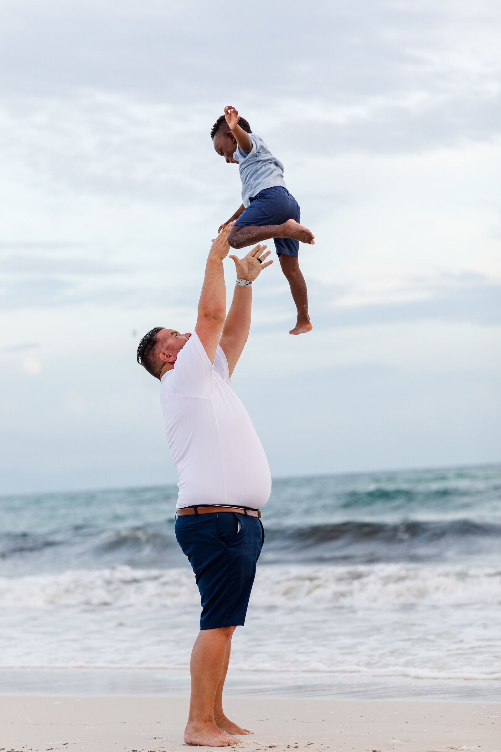 Father throwing son into the air on Pensacola Beach