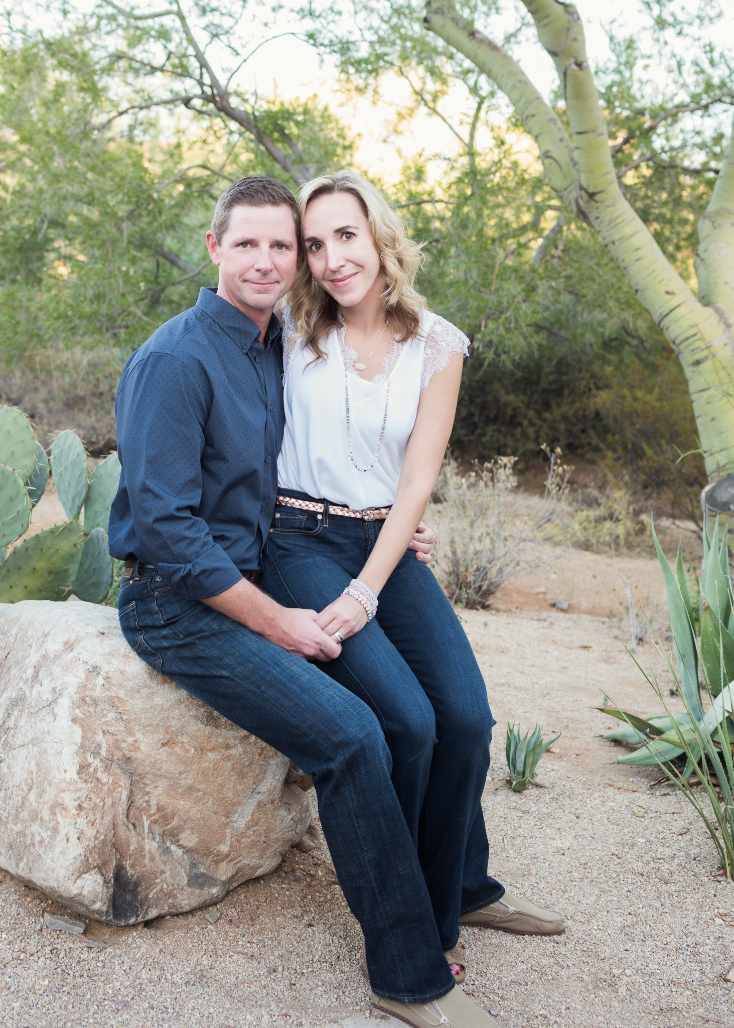 husband and wife sitting on a boulder in the desert