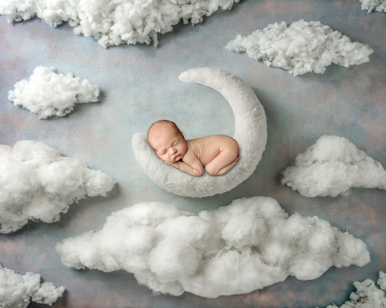 Baby boy posed on a moon with clouds in the quad cities