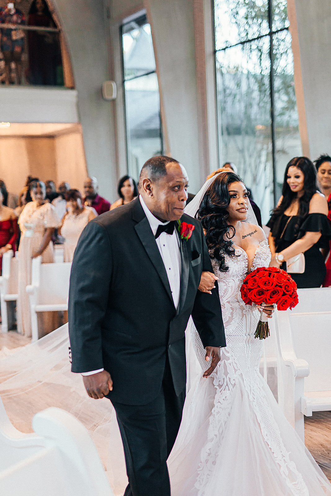 Father of the bride walking his daughter with red roses down the aisle