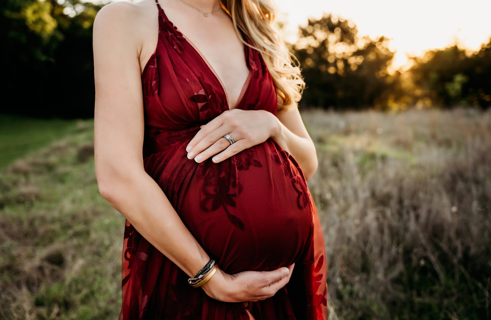 Maternity Photographer, an expectant mother places her hand on her belly to feel baby kick, she is outside