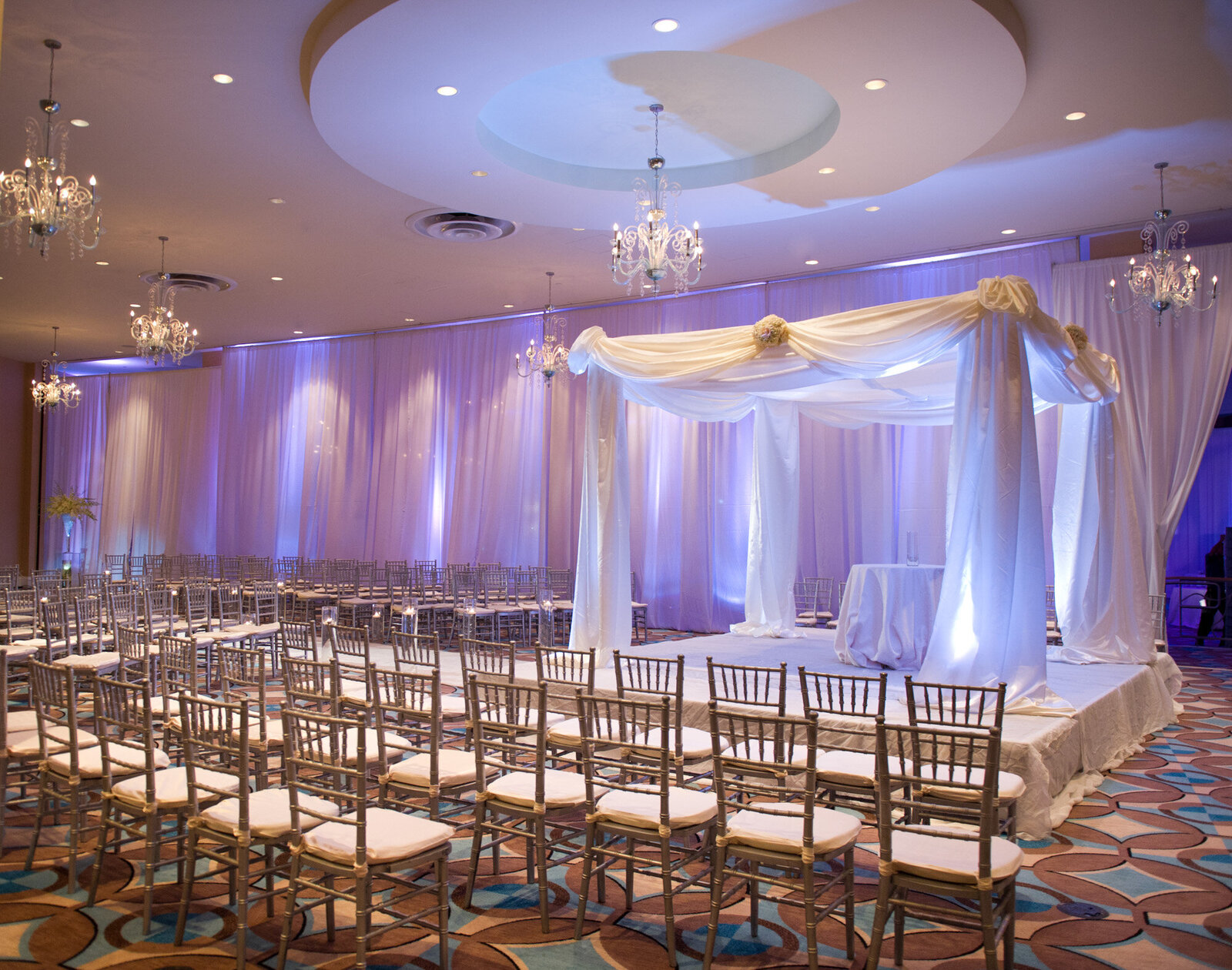 Luxurious wedding ceremony site with golden chairs and white drapings
