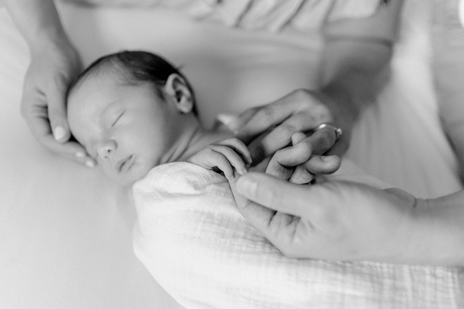 a black and white photo of a newborn baby boy holding his parents fingers