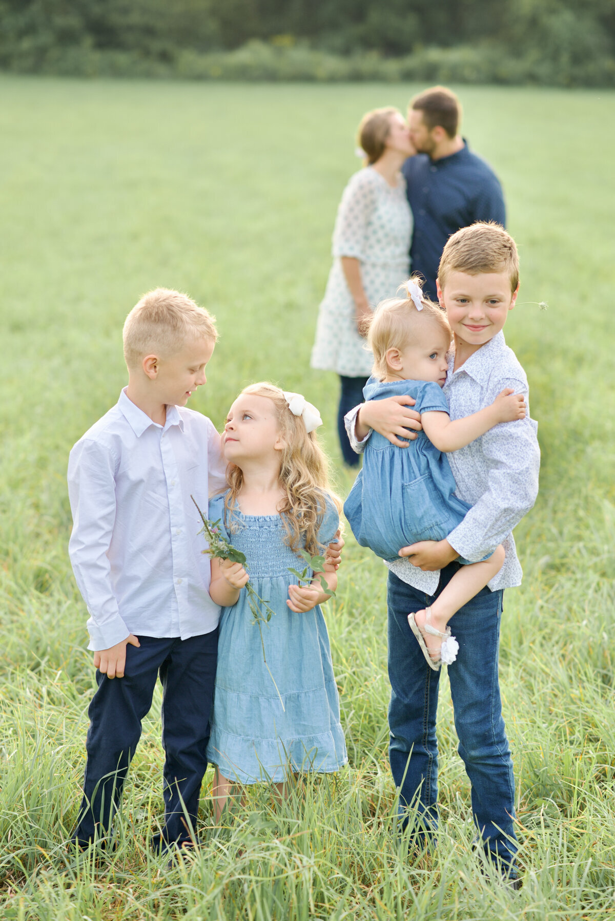 Kids with parents kissing in the background at a family photo session in mount vernon, ohio