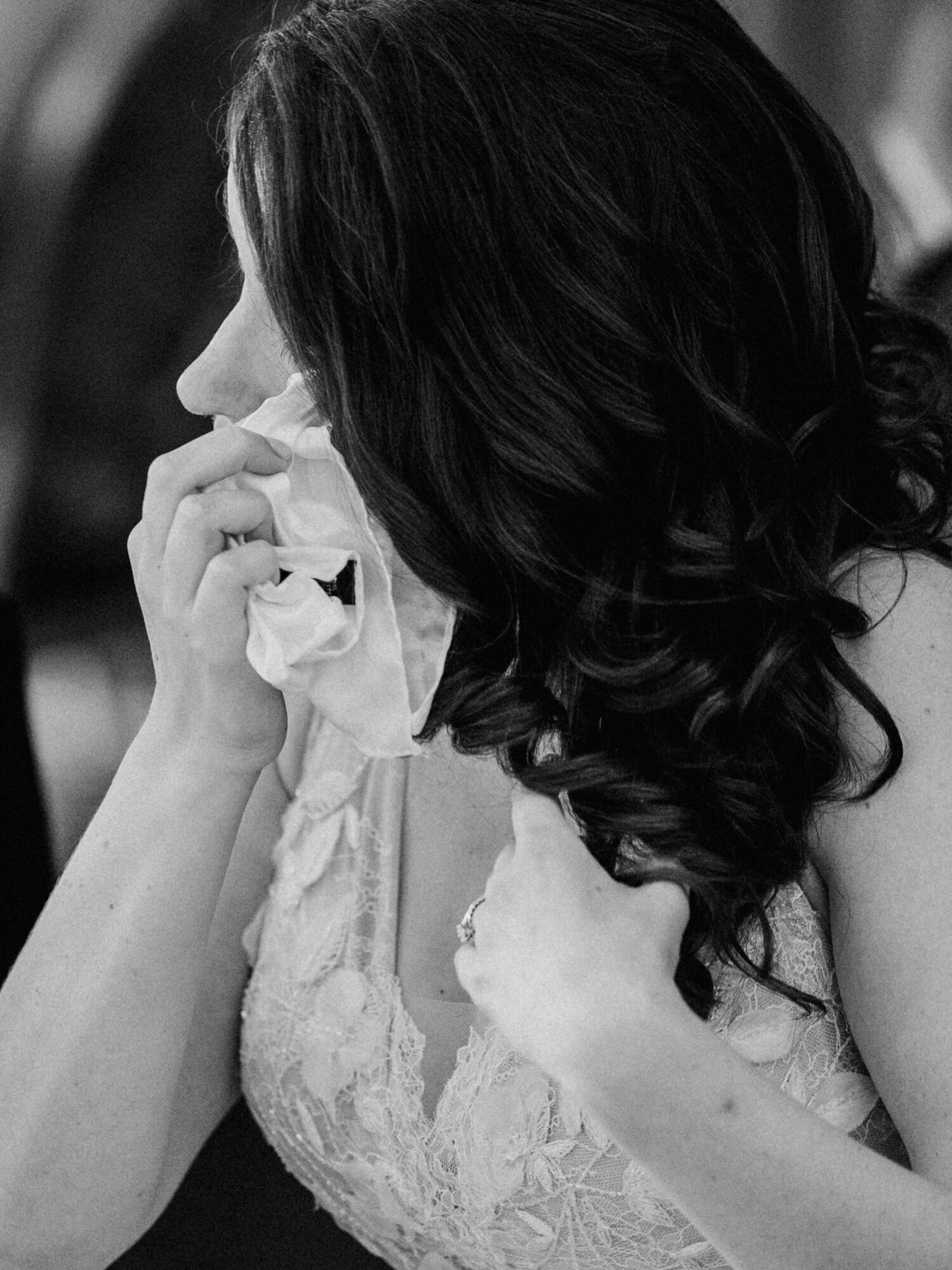 An emotional wedding reception photo of a bride shedding a tear during toasts given by her family