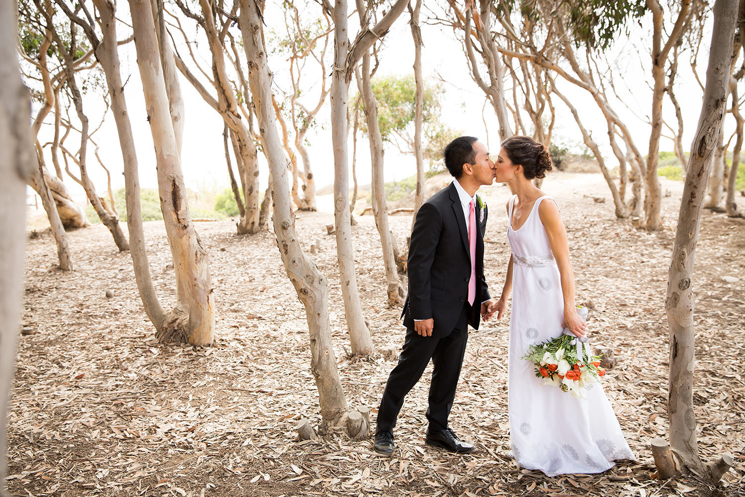 bride and groom kissing with trees at sunset cliffs
