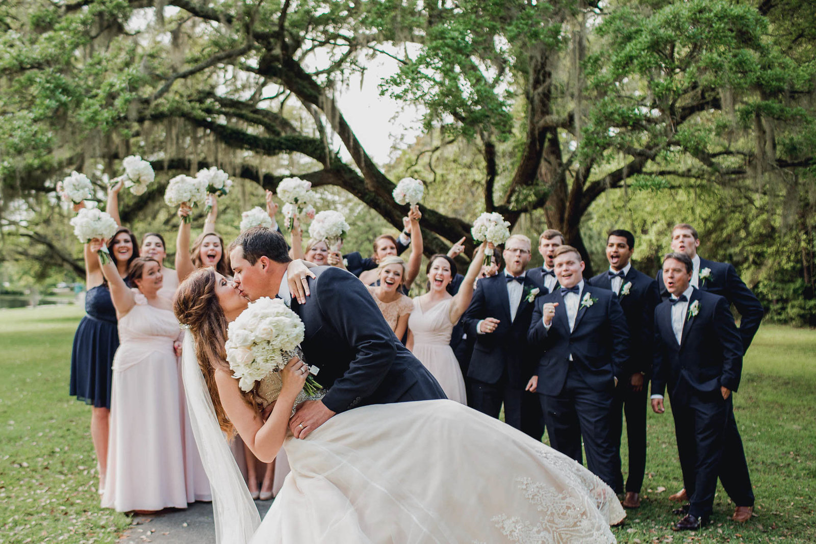 Bride and groom kiss while wedding party cheers, Brookgreen Gardens, Murrells Inlet, South Carolina. Kate Timbers Photography.