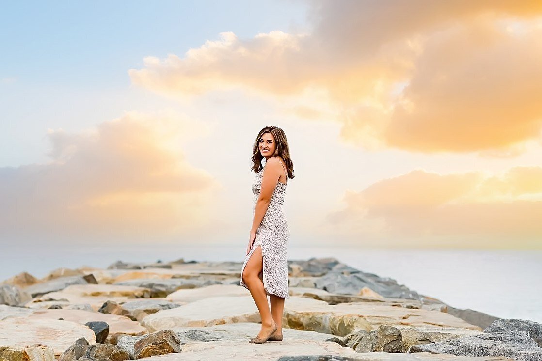 Senior portrait of a girl posing on the rock jetty in Carlsbad