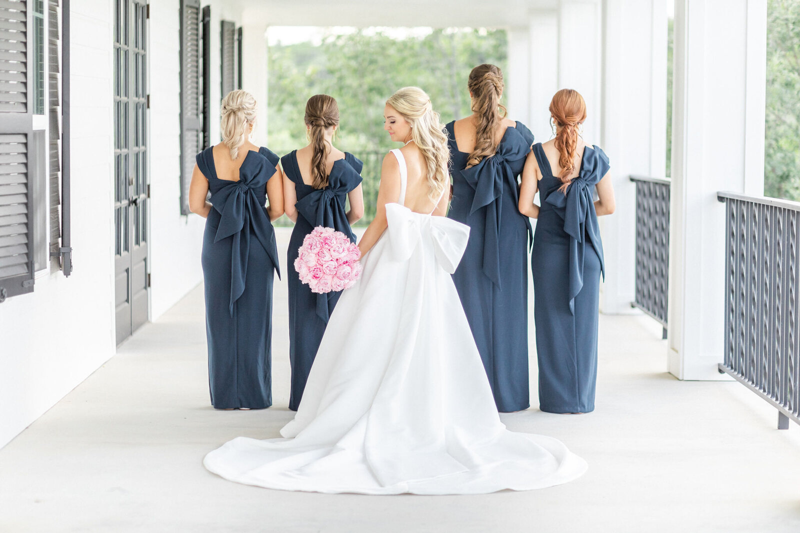 A bride and her bridesmaids posing on the Kendall Point wrap-around porch.