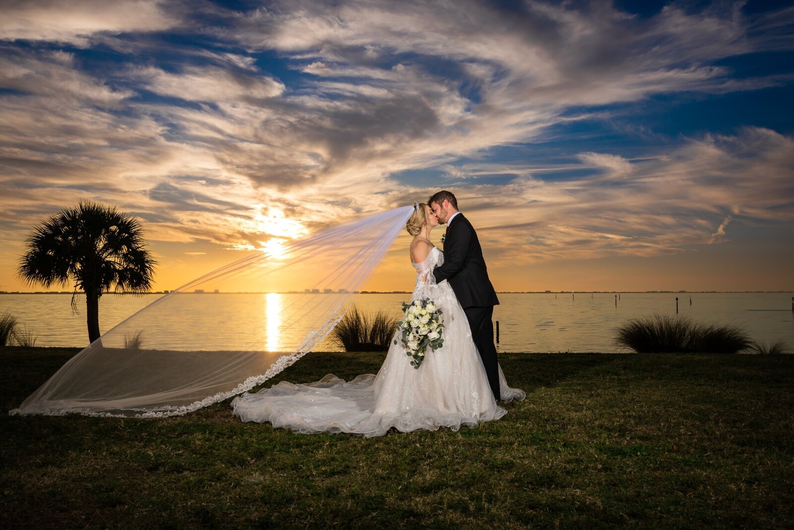 Bride and Groom kissing at The Powel Crosley with the sun setting over Sarasota Bay