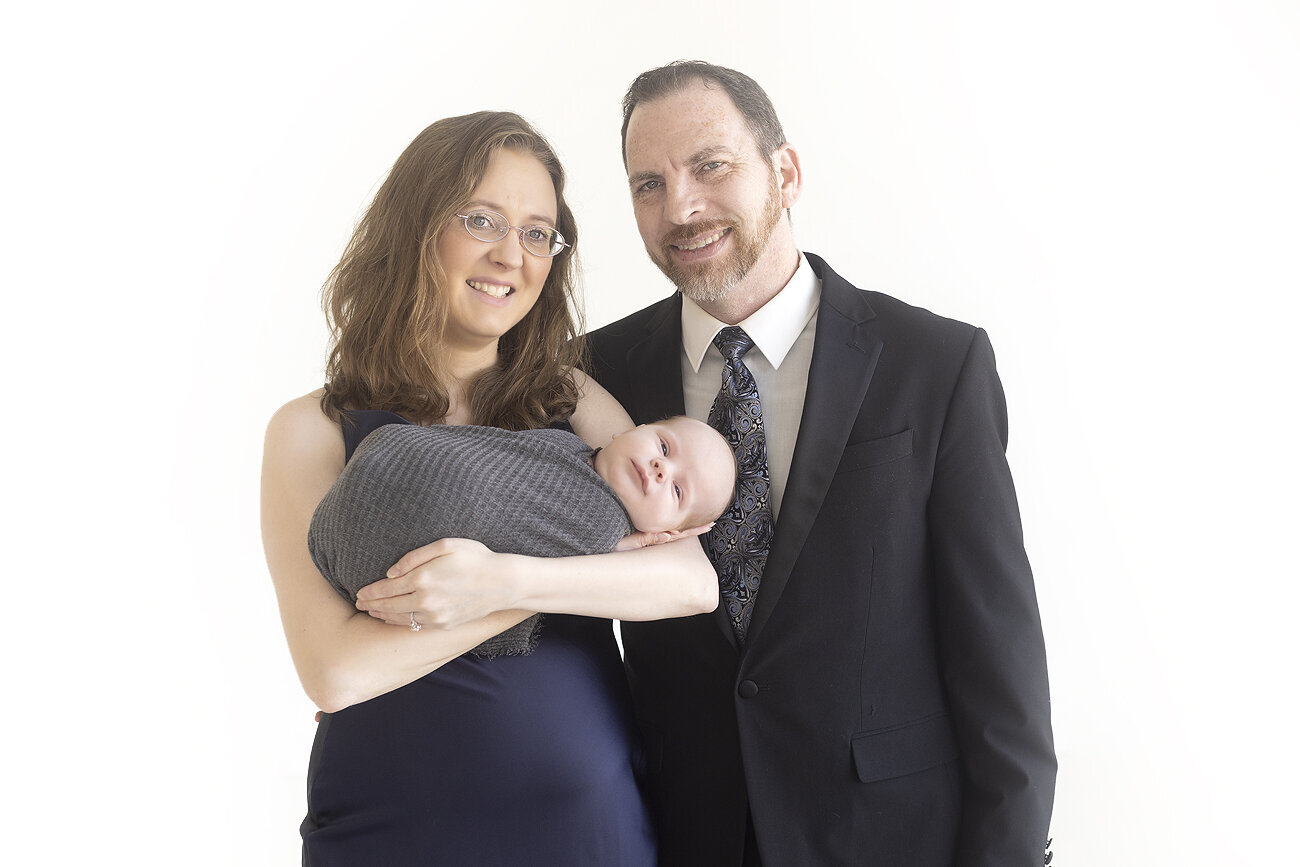 Formally dressed family holding newborn son, a Dallas newborn photographer.