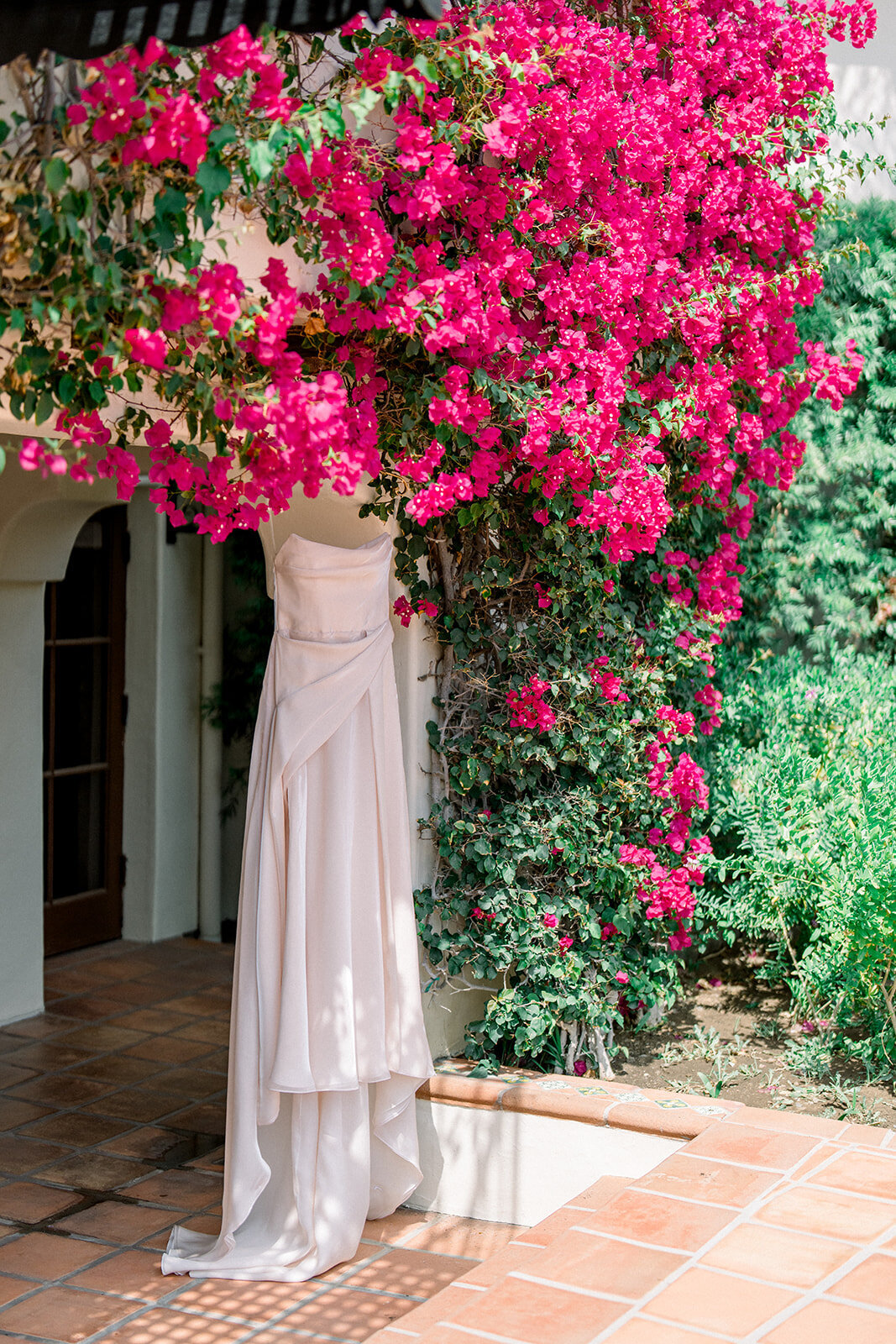 Bride stands beneath blooming bougainvillea in soft natural light, captured in fine art film wedding photography.