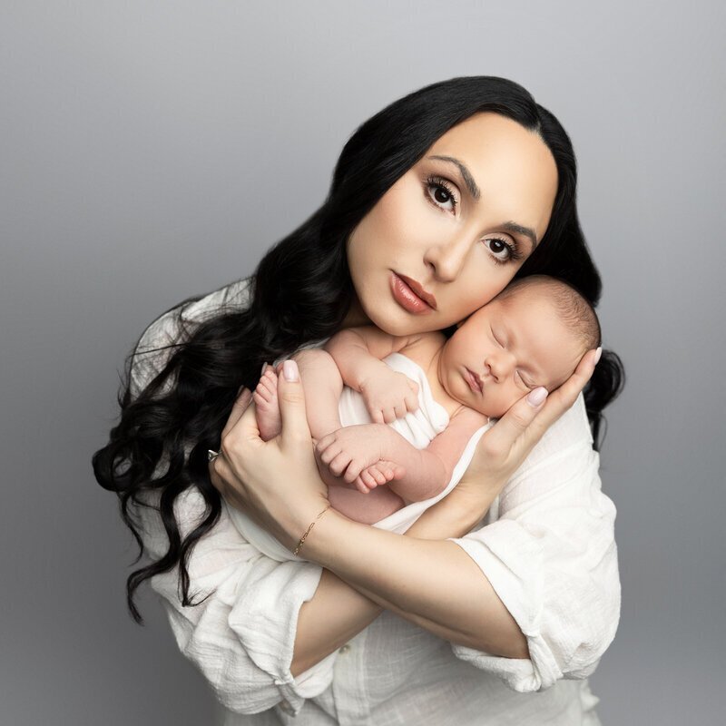 mom holding sleeping newborn baby taken by best newborn photographers nj
