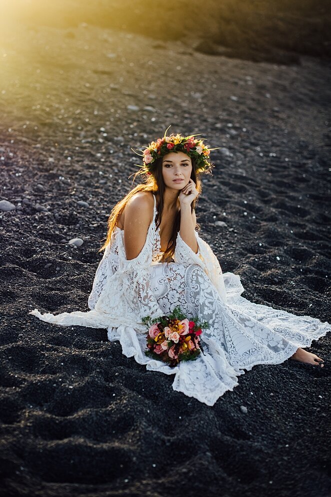 bride sitting on black sand beach on the big island