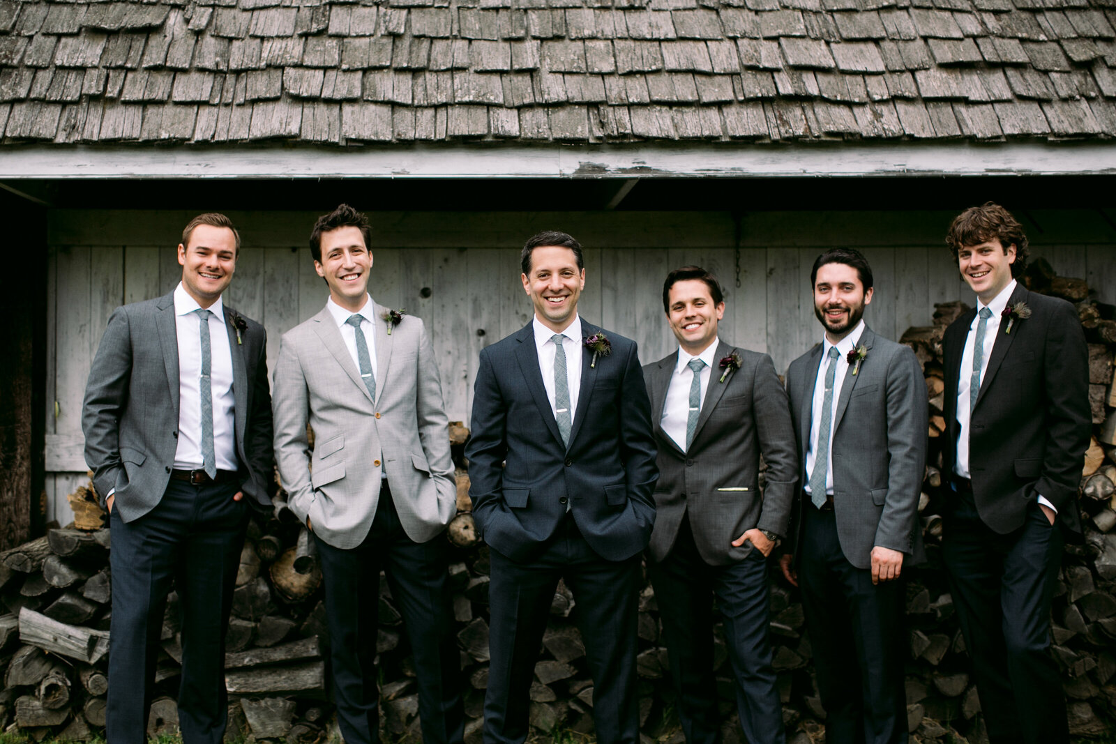 groomsmen at barn with wood pile