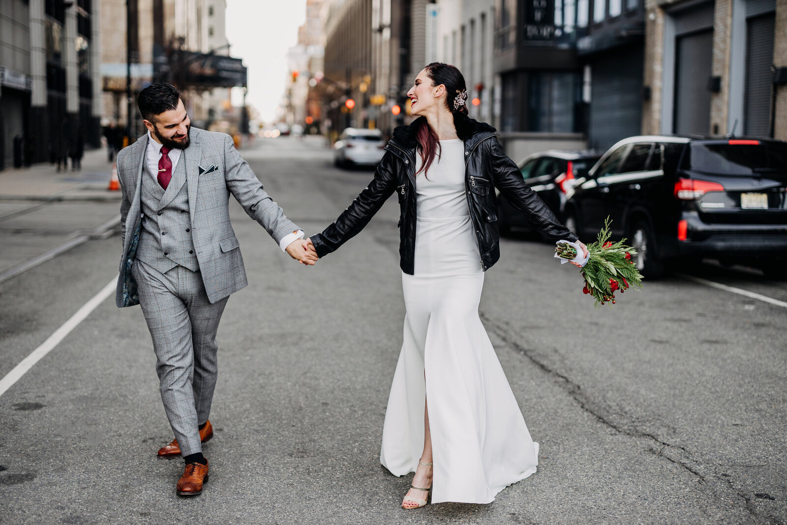bride with leather jacket and groom walking down city street