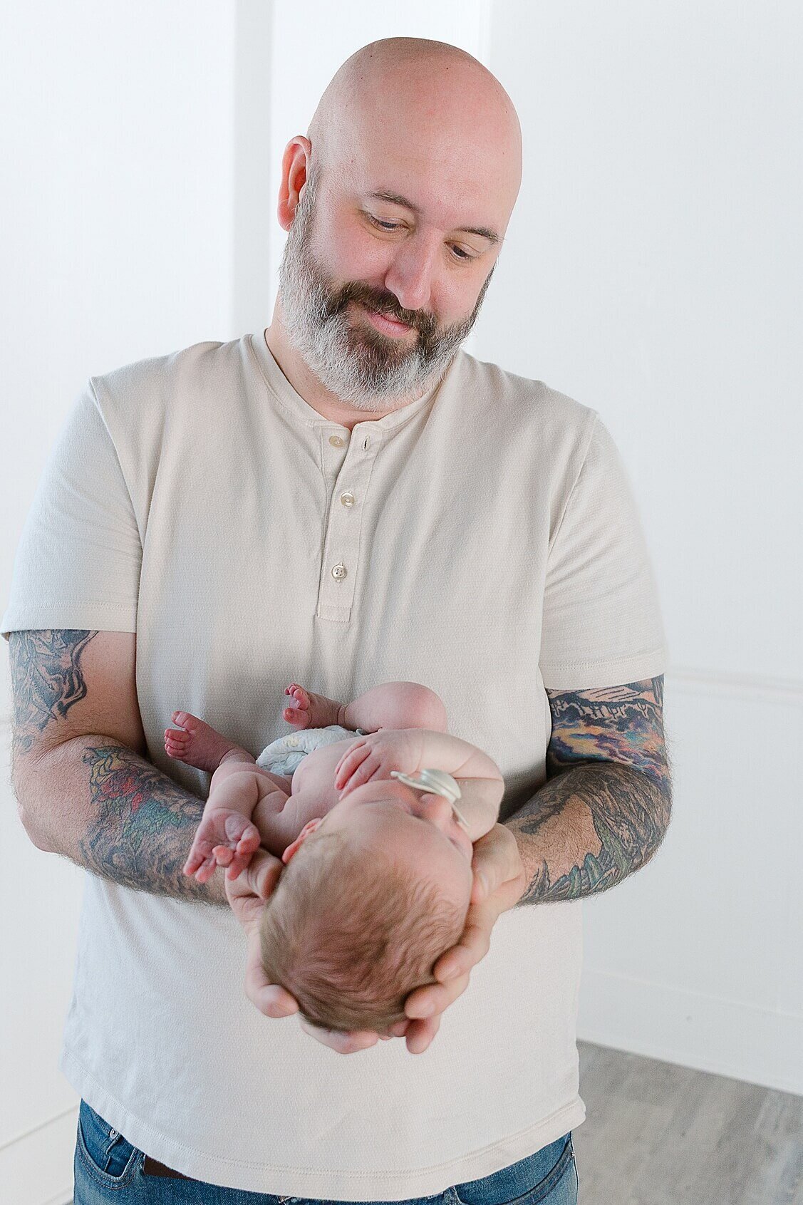 Dad is holding his baby boy in his hands.  Image taken during a studio Newborn Session in Wexford PA