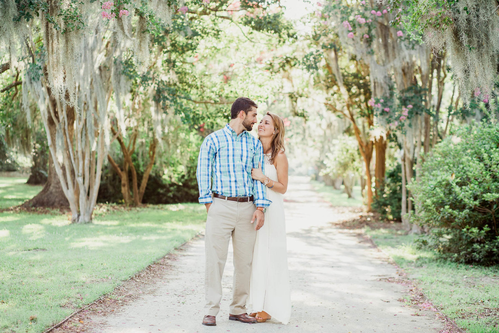 Engaged couple stands in clearing with spanish moss covered trees all around, Hampton Park, Charleston, South Carolina