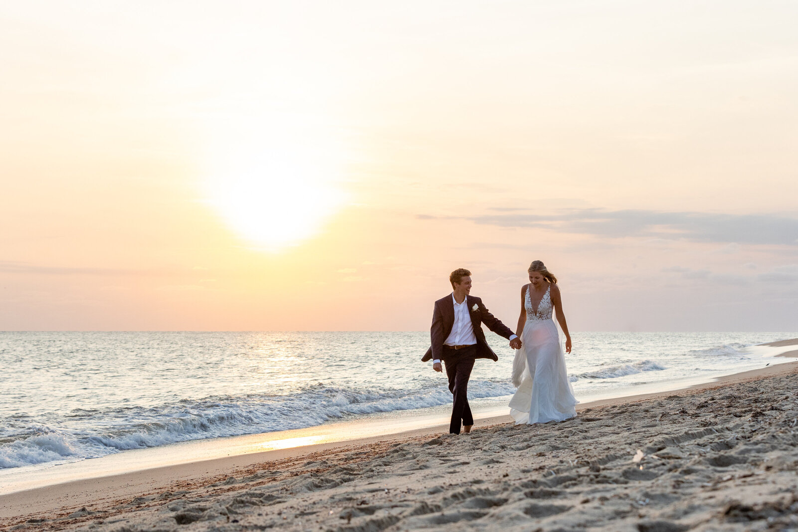 couple walks along  galley beach at sunset