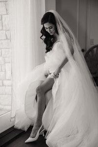 a bride slips on her garter prior to her wedding ceremony