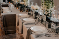 Décoration de table élégante et moderne pour un mariage au Café de l’Horloge, avec fleurs blanches, chandelles et vaisselle raffinée, photographiée par Jeff Gagnon photographe.