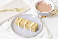 Slice of Earl Grey and Lavender cake on a lilac plate with a cup of tea
