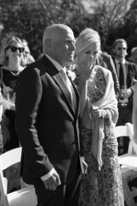Mother of the bride wipes away a tear during wedding ceremony.