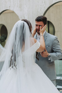 Catholic bride wipes her groom's tears as he sees her for the first time on their wedding day