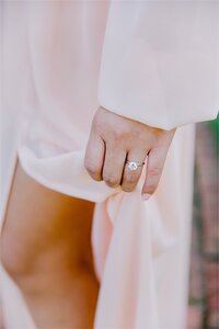 woman's hand closeup of the engagement ring featuring the woman holding pink dress above knee