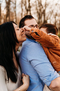 Mom and dad holding young son.  boy is pointing finger on mom's nose.  photo taken by Bethany Beach family photographer, Kristi