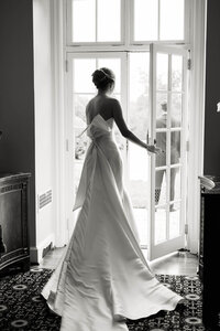 A refined composition of a bride in a statement gown standing in a sunlit doorway, captured with an editorial and intentional eye.