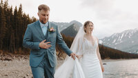 Couple shown walking and laughing along the shoreline of upper Kananaskis lake, Alberta.