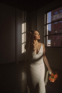 A person in a wedding dress looking out a window