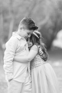 The Dilorio family children sharing a sweet hug, with a brother and sister embracing during a soft black and white outdoor family photography session in Las Vegas.