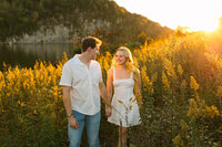 Couple walking through tall grass during golden hour in Knoxville Tennessee
